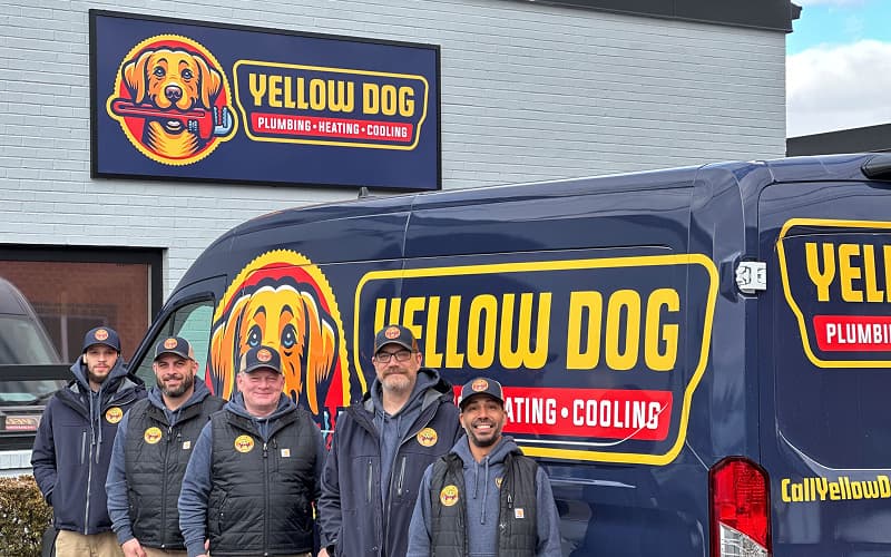 The Yellow Dog Plumbing, Heating & Cooling team in front of their service van